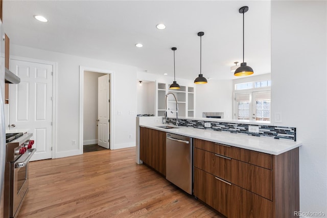 kitchen featuring sink, backsplash, appliances with stainless steel finishes, and hanging light fixtures