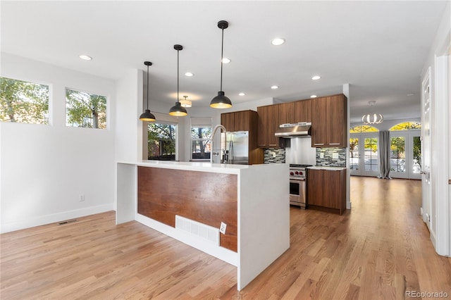 kitchen with light hardwood / wood-style flooring, french doors, decorative light fixtures, appliances with stainless steel finishes, and decorative backsplash