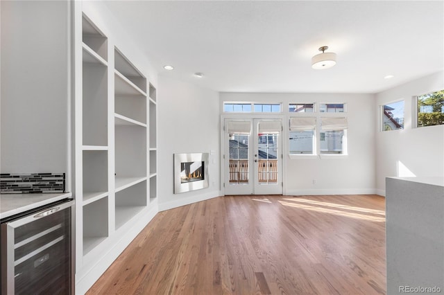 unfurnished living room with hardwood / wood-style flooring, built in features, and wine cooler