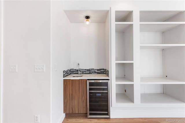 bar featuring sink, hardwood / wood-style floors, decorative backsplash, and beverage cooler