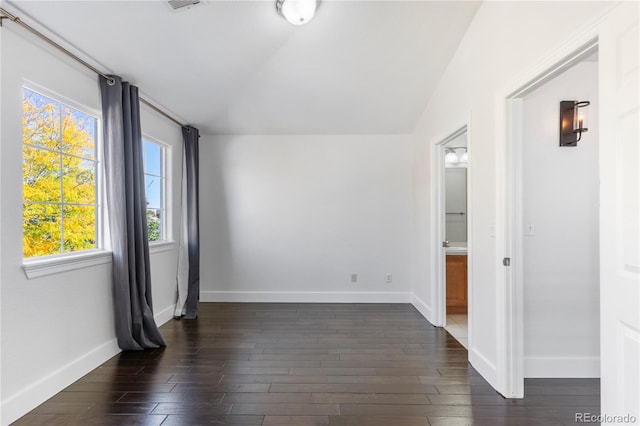 empty room featuring vaulted ceiling and dark hardwood / wood-style flooring