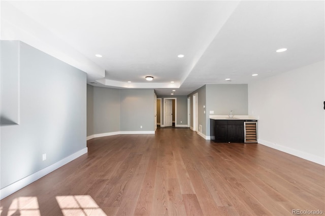 unfurnished living room with hardwood / wood-style floors, wet bar, and beverage cooler