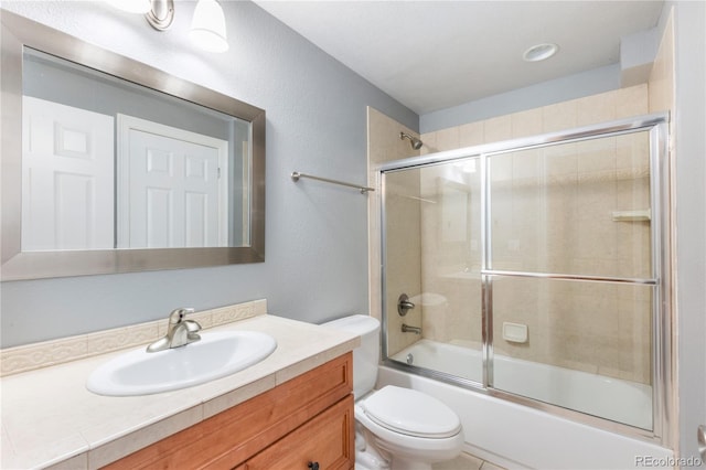 full bathroom with bath / shower combo with glass door, toilet, and vanity