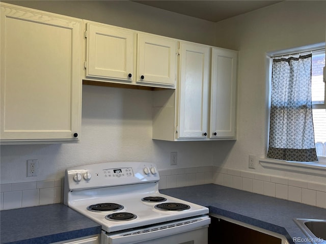 kitchen with white electric range, dark countertops, and white cabinetry