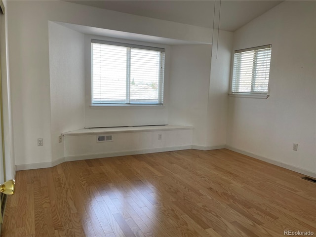 spare room with visible vents, baseboards, and wood finished floors