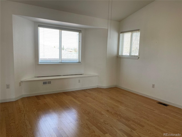 spare room featuring visible vents, baseboards, a healthy amount of sunlight, and light wood finished floors