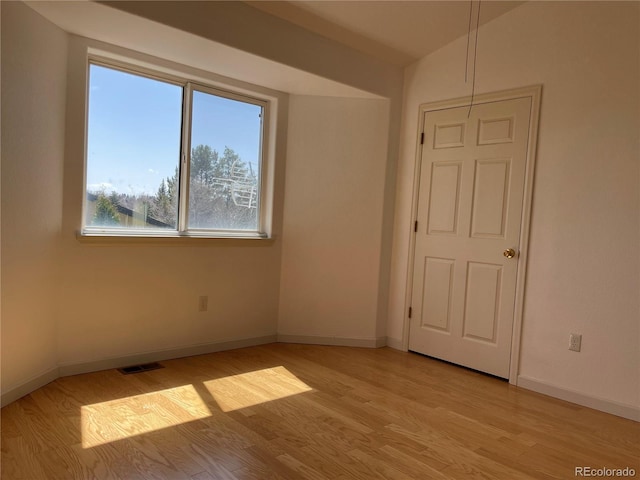 empty room featuring visible vents, light wood-style flooring, and baseboards