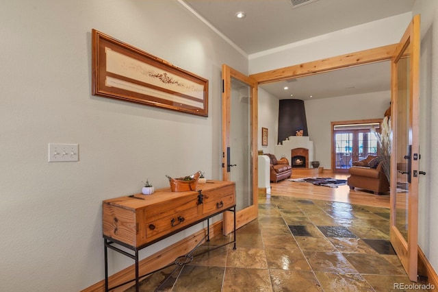 hallway with visible vents, french doors, stone tile flooring, and baseboards