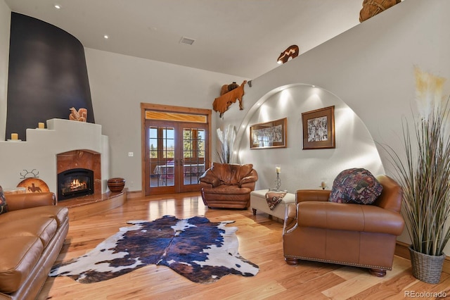 living area with a premium fireplace, visible vents, wood finished floors, and french doors