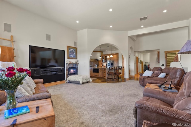 living area with recessed lighting, visible vents, arched walkways, and light colored carpet