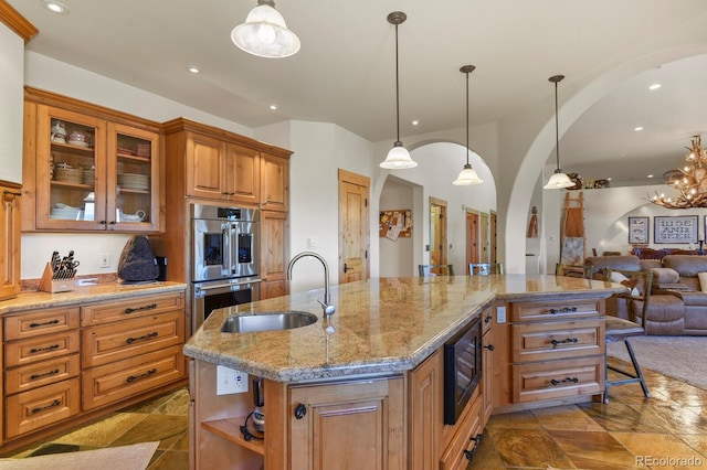 kitchen featuring black microwave, double oven, arched walkways, a sink, and open floor plan