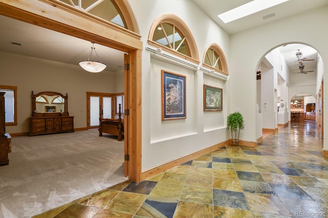 hall with carpet, a high ceiling, arched walkways, and visible vents