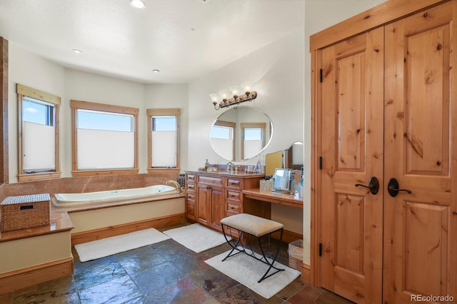 full bathroom with plenty of natural light, a garden tub, vanity, and stone tile floors