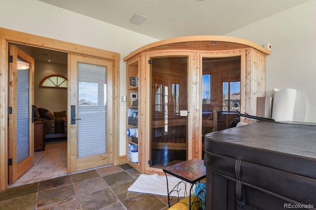 interior space with arched walkways, stone tile flooring, and french doors