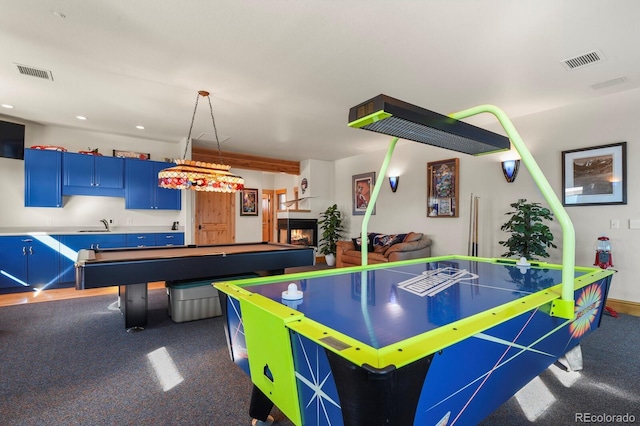 rec room with a sink, a glass covered fireplace, and visible vents