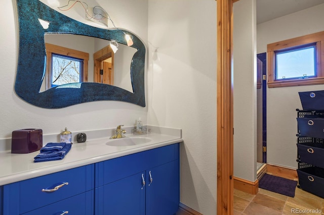 bathroom featuring a stall shower, a healthy amount of sunlight, vanity, and baseboards