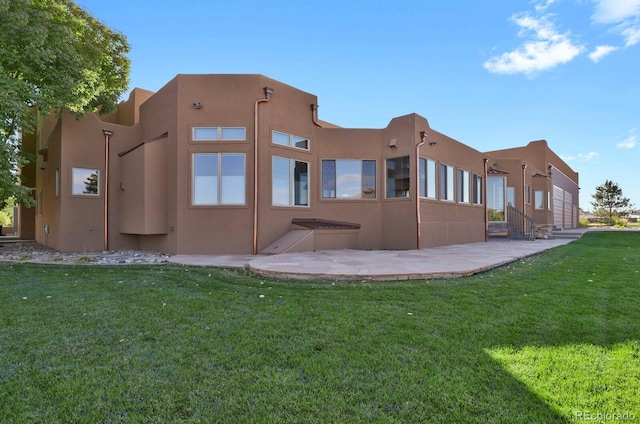 rear view of house featuring entry steps, a yard, a patio area, and stucco siding