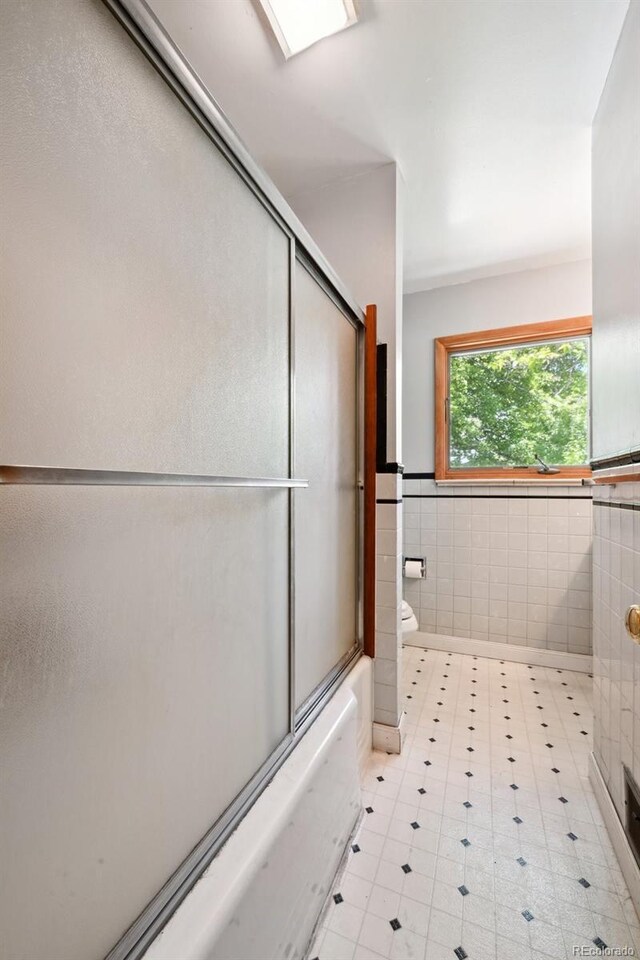 6050 Marshall Ct, Arvada, CO 80003 - full bathroom featuring tile walls, toilet, wainscoting, and combined bath / shower with glass door