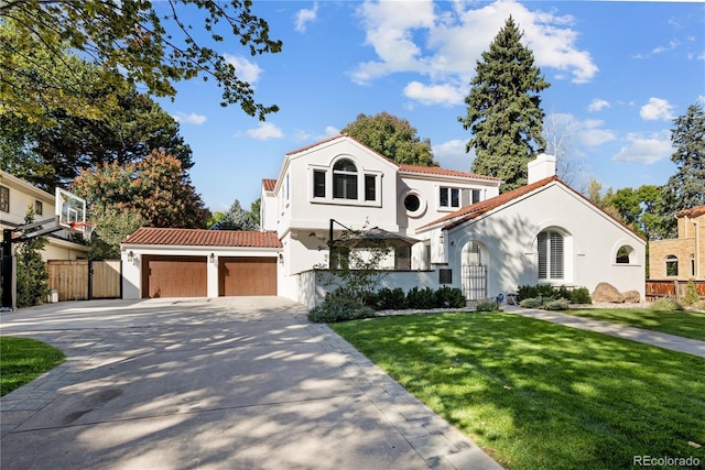 mediterranean / spanish house featuring a front lawn, stucco siding, a garage, and fence