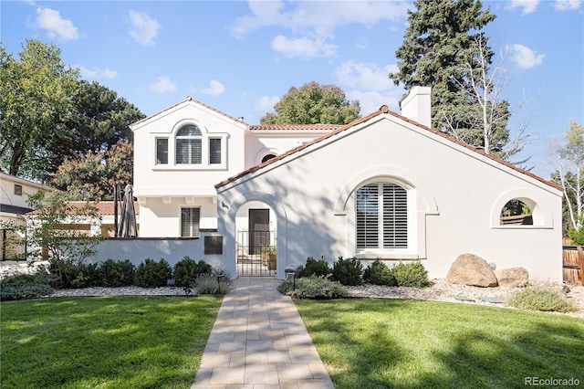 mediterranean / spanish home with a fenced front yard, stucco siding, a gate, and a front yard
