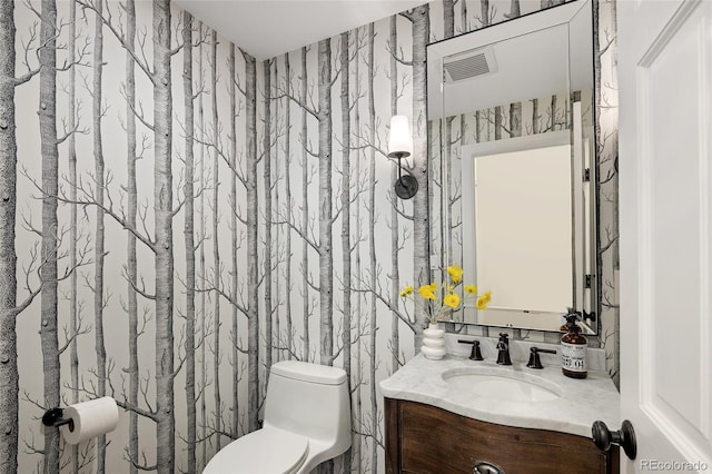 bathroom featuring wallpapered walls, toilet, and vanity