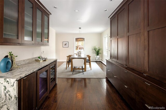 kitchen with light stone counters, dark wood-type flooring, dark brown cabinetry, glass insert cabinets, and baseboards