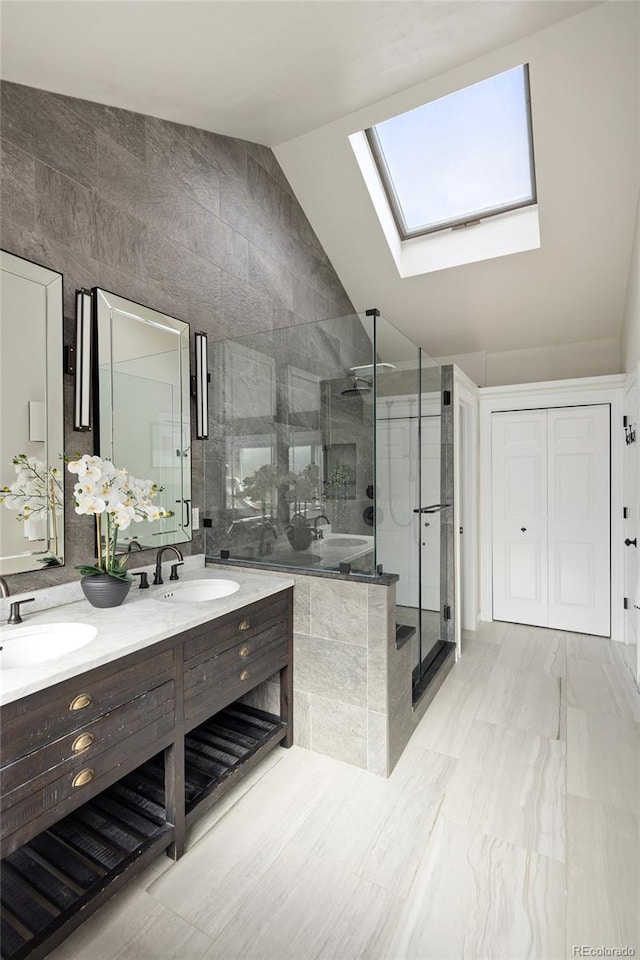 full bathroom with a stall shower, lofted ceiling with skylight, double vanity, and a sink