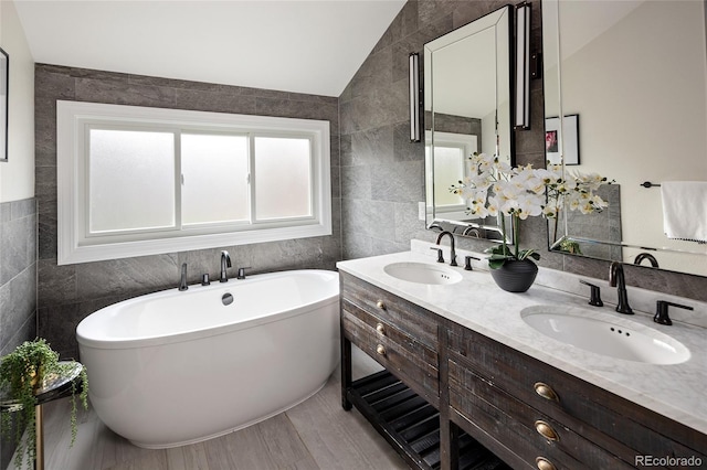 full bathroom featuring lofted ceiling, tile walls, and a sink