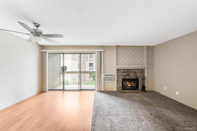 4896 S Dudley St Unit 4-7, Littleton, CO 80123 - unfurnished living room featuring a fireplace, a textured ceiling, ceiling fan, and a wall unit AC