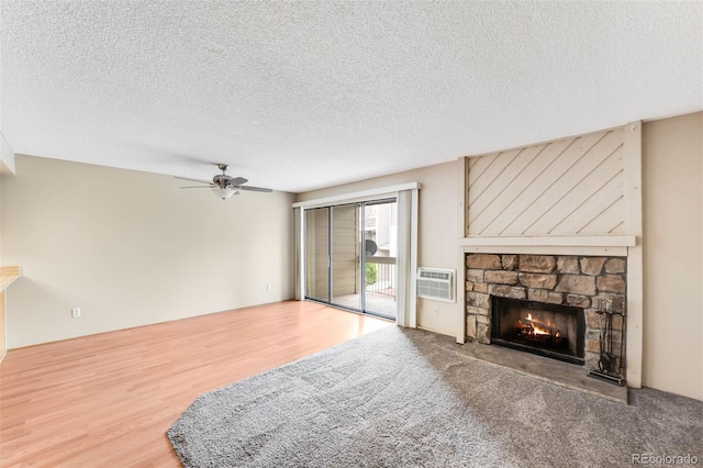 4896 S Dudley St Unit 4-7, Littleton, CO 80123 - unfurnished living room with ceiling fan, a stone fireplace, an AC wall unit, a textured ceiling, and wood finished floors