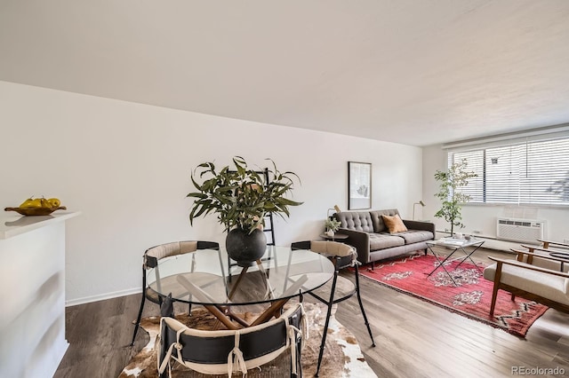 dining room with baseboards, an AC wall unit, and wood finished floors