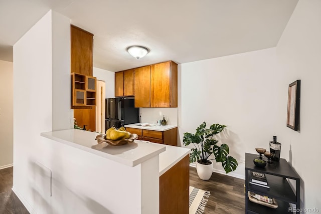 kitchen featuring brown cabinetry, dark wood-style floors, light countertops, and freestanding refrigerator