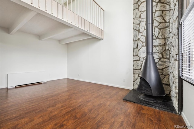 384 S Ironton St Unit 413, Aurora, CO 80012 - unfurnished living room with wood finished floors, beam ceiling, a wood stove, and baseboards