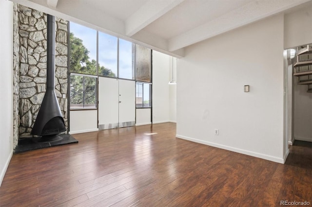 384 S Ironton St Unit 413, Aurora, CO 80012 - unfurnished living room featuring baseboards, wood finished floors, beamed ceiling, and a wood stove