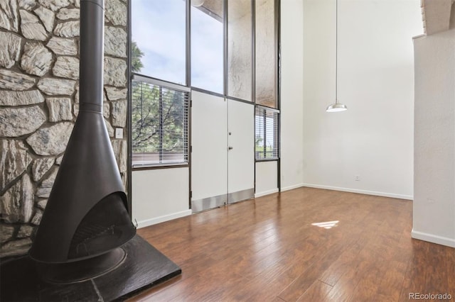 384 S Ironton St Unit 413, Aurora, CO 80012 - unfurnished living room with a wood stove, wood finished floors, baseboards, and a towering ceiling