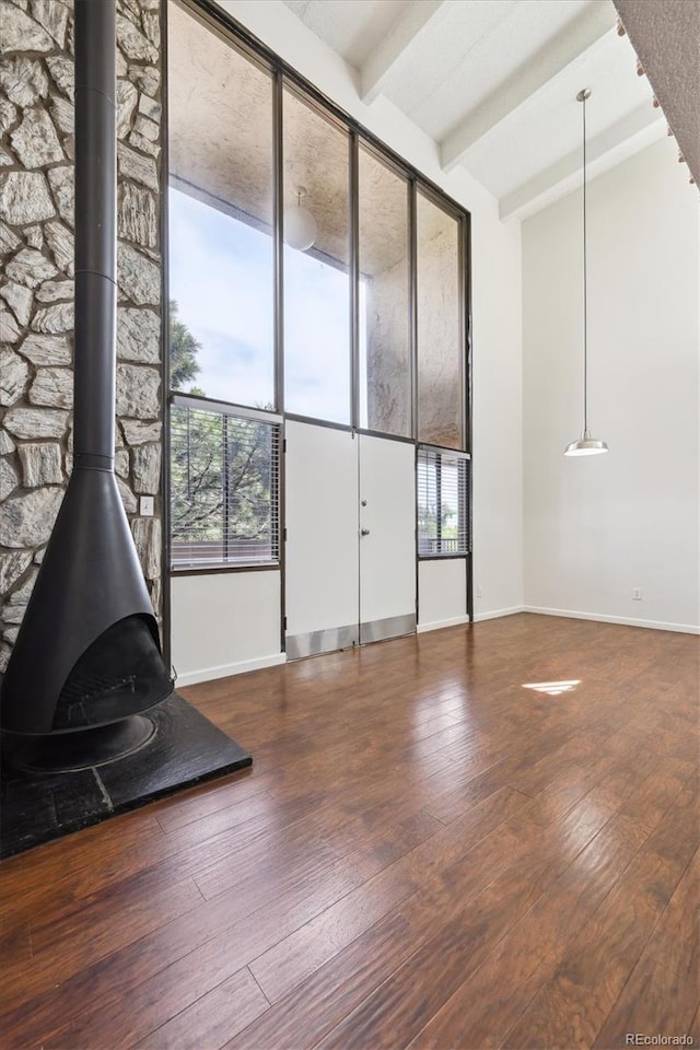 384 S Ironton St Unit 413, Aurora, CO 80012 - unfurnished living room with a wood stove, beamed ceiling, wood-type flooring, and baseboards