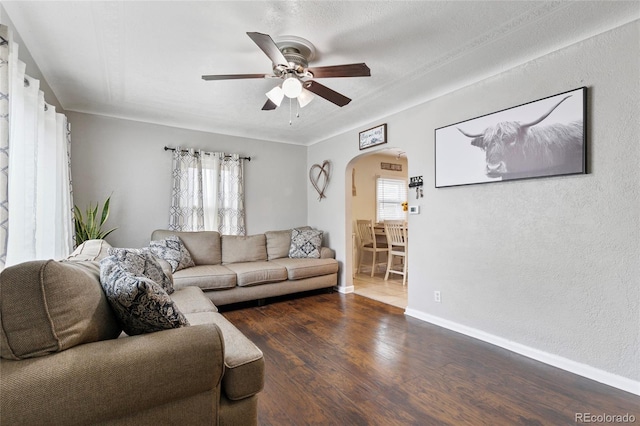 5910 Glencoe St, Commerce City, CO 80022 - living area with arched walkways, a ceiling fan, a healthy amount of sunlight, and wood finished floors