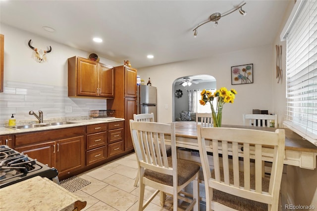 5910 Glencoe St, Commerce City, CO 80022 - kitchen with freestanding refrigerator, arched walkways, ceiling fan, a sink, and backsplash