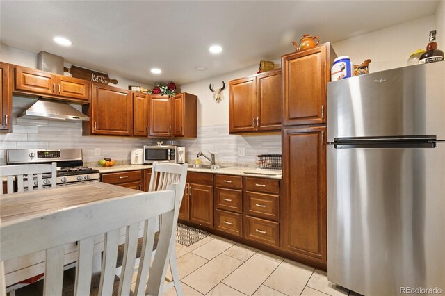 5910 Glencoe St, Commerce City, CO 80022 - kitchen featuring a sink, under cabinet range hood, decorative backsplash, light countertops, and appliances with stainless steel finishes