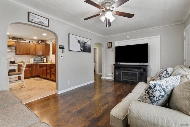 5910 Glencoe St, Commerce City, CO 80022 - living room featuring visible vents, wood finished floors, a ceiling fan, and arched walkways