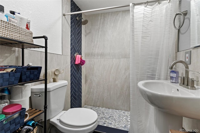5910 Glencoe St, Commerce City, CO 80022 - bathroom with a sink, tile walls, toilet, and a tile shower