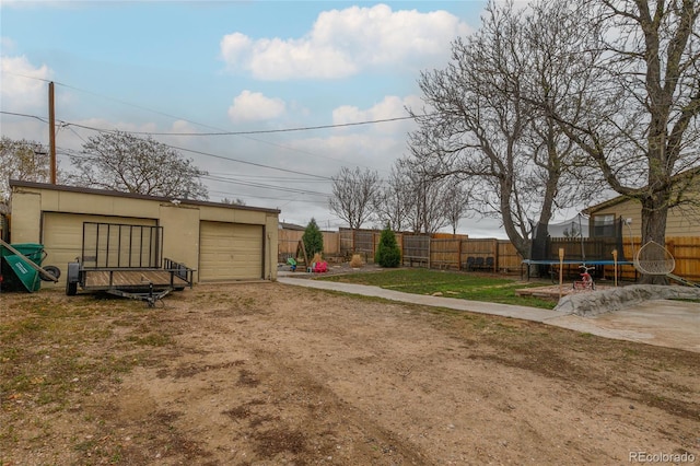 5910 Glencoe St, Commerce City, CO 80022 - view of yard with a trampoline, driveway, fence, and a garage