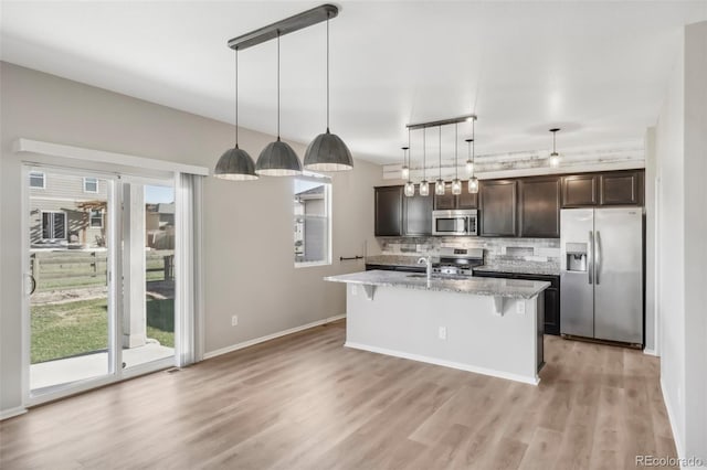 kitchen with stainless steel appliances, tasteful backsplash, pendant lighting, a breakfast bar area, and dark brown cabinets