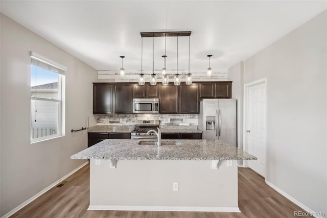 kitchen with a kitchen bar, stainless steel appliances, and a kitchen island with sink