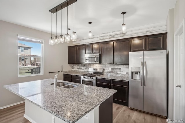 kitchen with sink, a center island with sink, dark brown cabinets, and appliances with stainless steel finishes