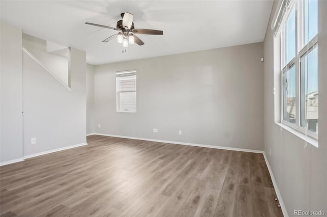 empty room with hardwood / wood-style floors, ceiling fan, and a healthy amount of sunlight