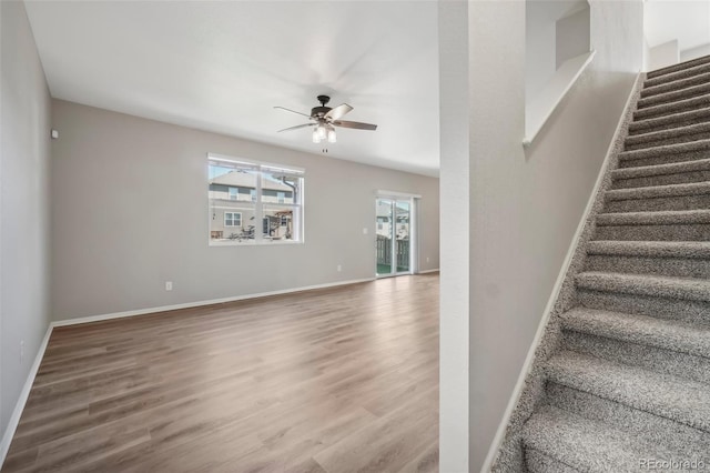 stairway with hardwood / wood-style flooring and ceiling fan