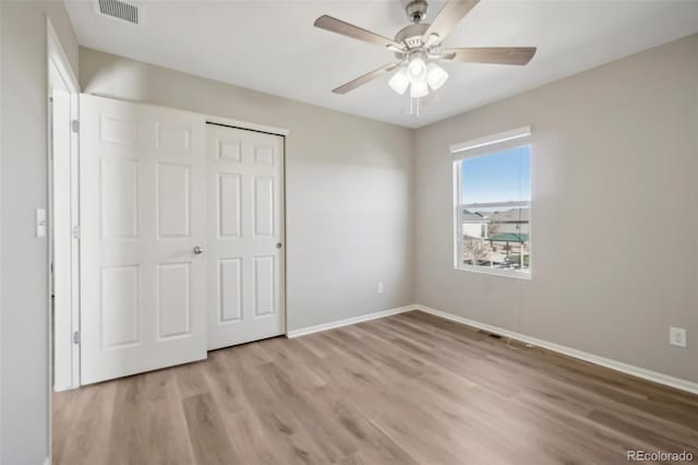 unfurnished bedroom with ceiling fan, a closet, and light wood-type flooring