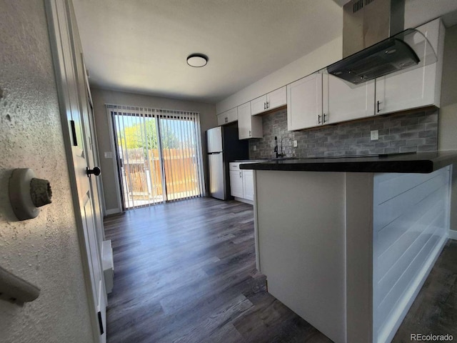 25 Castle Royal Dr, Pueblo, CO 81005 - kitchen featuring range hood, dark wood finished floors, dark countertops, freestanding refrigerator, and decorative backsplash