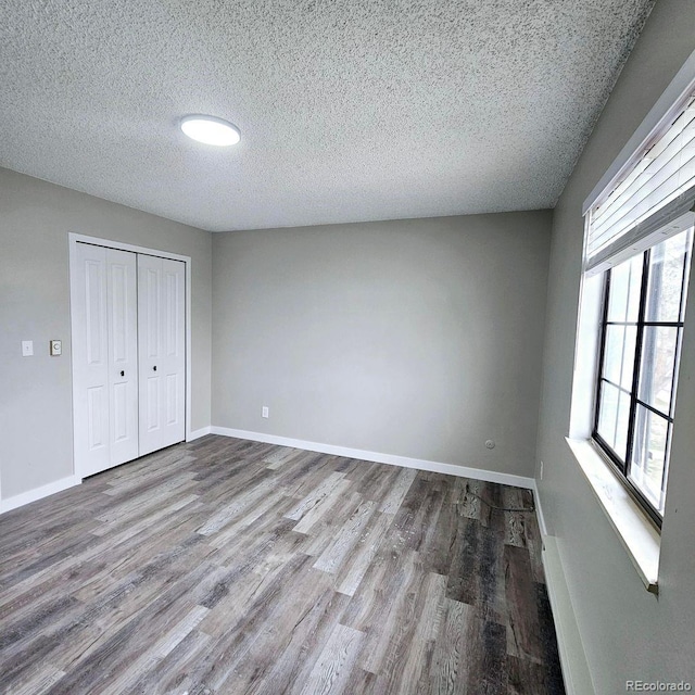 25 Castle Royal Dr, Pueblo, CO 81005 - unfurnished bedroom with a textured ceiling, wood finished floors, a closet, and baseboards